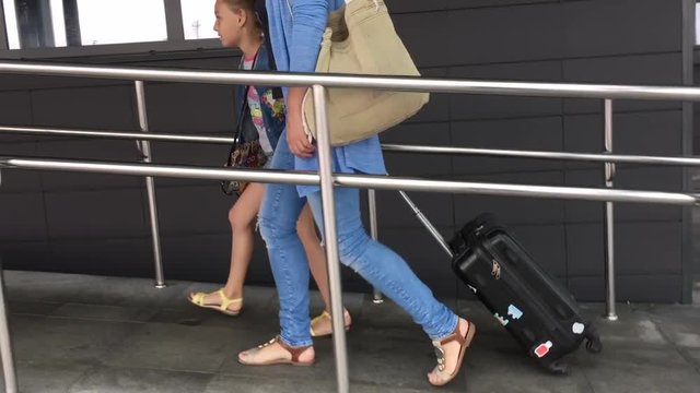 Young mother and daughter teenager with suitcase coming to airport terminal