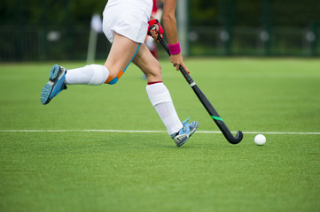 Young hockey player woman with ball in attack playing field hockey game