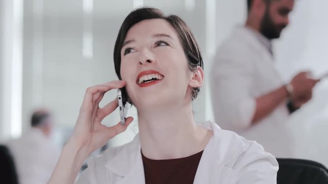 Portrait of smiling beautiful nurse talking on phone with clients of gynecological clinic. Woman gynecologist talking with patient on mobile phone