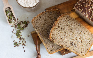 Sliced whole grain rye bread with seeds on wooden cutting board. 