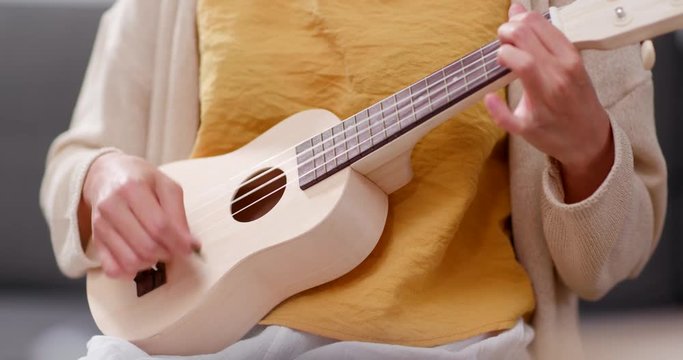 Woman play a song with ukulele at home