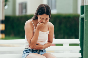 Portrait of young woman sick vomiting outdoors