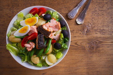 Salad Nicoise with salmon. Tomato, green beans, new potato, olives and lettuce salad with salmon. overhead, horizontal