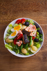 Salad Nicoise with salmon. Tomato, green beans, new potato, olives and lettuce salad with salmon. overhead, vertical