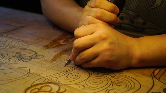 Chinese wood block art carving by hand. Asian artisan preparing woodblock for printing patterns on rice paper. Tang Dynasty technique of print cutting, ancient art in China.