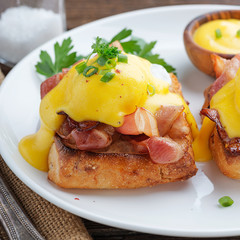 Eggs benedict with bacon on wooden background . 