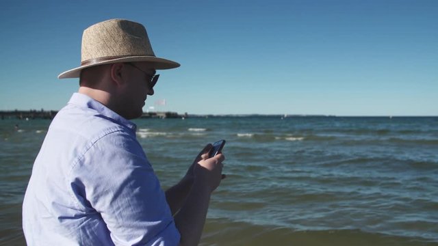 Man in straw hat taking pictures of sea 4K