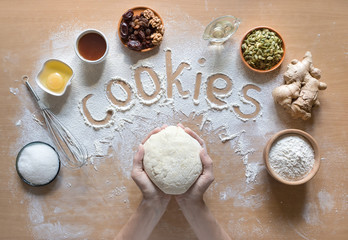 Word Cookie written on flour and top view of product set for cooking 
