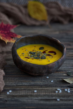 Pumpkin cream soup with pumpkin seeds on a dark background. Rustic style