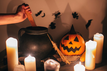 Happy Halloween. witch hand boiling potion for spell, with jack o lantern pumpkin with candles,...