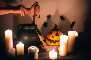 Happy Halloween. witch hand boiling potion for spell, with jack o lantern pumpkin with candles,...