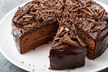 Sliced tasty chocolate cake on wooden background.