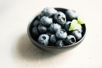 Blueberries, summer season, berries in black bowl. Selective focus, toned image, closeup.