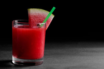 Watermelon smoothies in a glass with a slice of watermelon on a black background with a place for writing