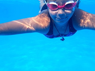 The girl smiles, swimming under water