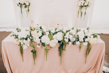 stylish wedding setting, tender pink table centerpiece with modern flowers bouquets, with glasses,cutlery,napkin and delicious food and drinks. luxury catering in restaurant. wedding reception