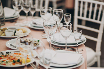 stylish pink table with wine glasses, cutlery, napkin and delicious food and drinks. luxury catering in restaurant. modern wedding reception. pink and white wedding settings