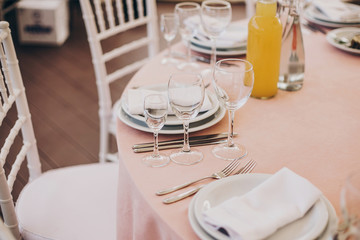 stylish wedding setting, tender pink table with wine glasses, cutlery, napkin and delicious food and drinks. luxury catering in restaurant. modern wedding reception