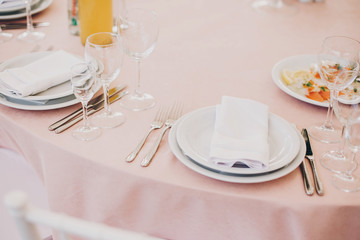 stylish pink table with wine glasses, cutlery, napkin and delicious food and drinks. luxury catering in restaurant. modern wedding reception. pink and white wedding settings