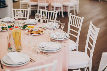 stylish pink table with wine glasses, cutlery, napkin and delicious food and drinks. luxury catering in restaurant. modern wedding reception. pink and white wedding settings