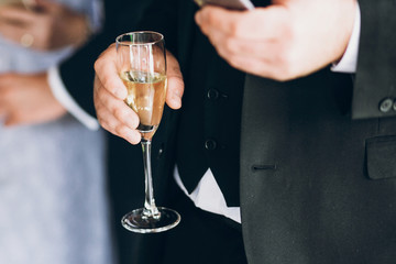 hands of stylish people cheering with glasses of champagne, luxury wedding reception, rich celebration.  guests toasting at christmas luxury celebration feast