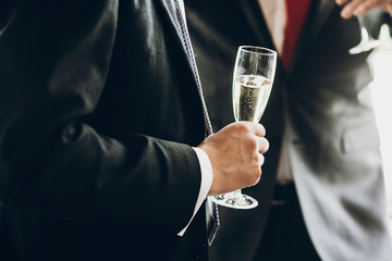 hands of stylish people cheering with glasses of champagne, luxury wedding reception, rich celebration.  guests toasting at christmas luxury celebration feast