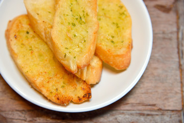Plate with garlic bread on wooden table. Selective focus.