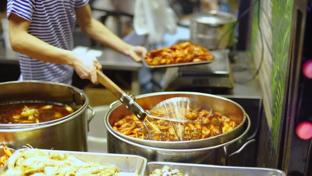 Crayfish being cooked and served in Shanghai. Chinese roadside restaurants serving seafood in downtown asian urban center. Different types of crawfish on display for sale.