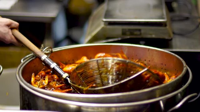 Shanghai shouning rd xiaolongxia cooking pot. Crayfish being cooked at street side restaurant in Asian downtown urban center kitchen. Large ladle stirs seafood.
