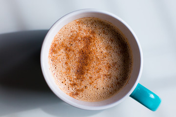 Tea latte in a blue mug with foam and cinnamon 