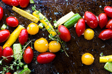 Cherry tomatoes, zucchini, and thyme on baking sheet