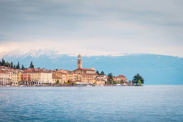 Coastal town Gargnano on Lake Garda, historic pastel-colored buildings and church tower next to the waterfront, Italy