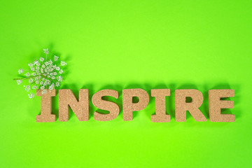 inspire text in cork with Queen Anne Lace on neon green background