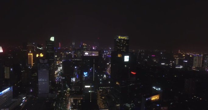 Flying around Nanjing East rd Kerry Center buildings in downtown. Shanghai China cityscape drone flying at night, with city lights and traffic on streets. Night time flying cityscape shot.