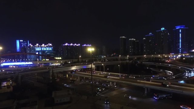 Flying up panning down on Shanghai elevated highway at night. Drone footage of downtown traffic on Chinese freeway interchange in evening.