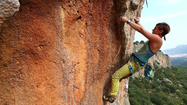 young woman rock climber climbing on the cliff. female climber climbing very hard route making hard moves,