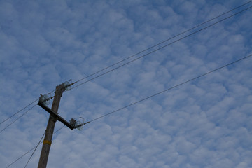 Electric pole under cloudy sky
