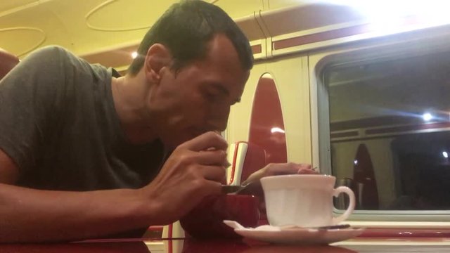 man at night eating soup in the train restaurant railway cat drinks coffee. man on the train concept journey travel railway lifestyle