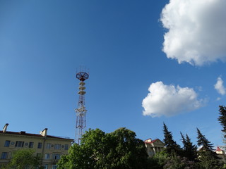 Fototapeta na wymiar Minsk, tower, telecommunications, journalism, television, broadcasting, satellite, antenna, ONT, TV channels, view from Victory Square, after houses, roofs, bright sky, clouds, trees.