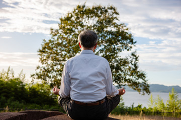 Fototapeta na wymiar A man of elderly who meditates outdoors