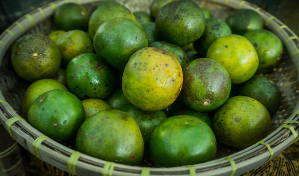 a green orange on the bamboo or wooden basket in traditional market in central java with warm color
