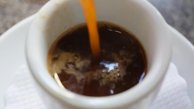 Close-up of a white coffee cup as traditional greek coffee is poured into the cup