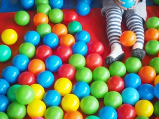 Lower half of a young girl child having playing with colorful plastic balls on children's playground