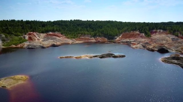 flock of birds fly over water pond in clay quarry pit