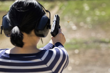 Woman shoots pistol at range.