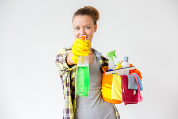 Woman in protective gloves is smiling and wiping dust using a spray and a duster