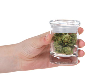 Young female hand holding glass jar with fresh marijuana buds. A psychoactive drug from the Cannabis plant used for medical or recreational purposes. Now legal in California