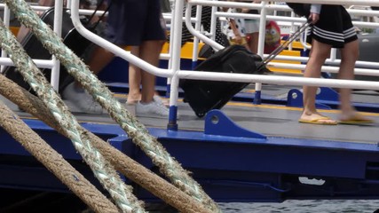 Low angle view of travelers legs as they disembark a cruise ship with their luggage in tow