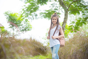 Beautiful asian girl with backpack standing and smiles in park