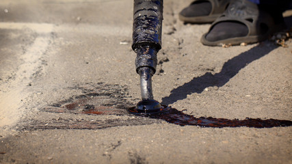 Workers repair the road, pour small cracks with bitumen to prevent further destruction of the road...